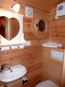 Baño en una cabaña de madera con lavabo y espejo en Gites et Roulottes Du Grand Puits, en Saint-Laurent-dʼAigouze