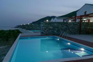 a swimming pool in front of a house at ANEFANTI VILLAS in Agios Kirykos