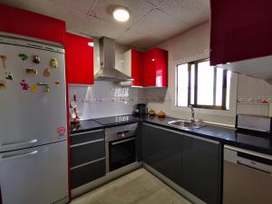 Il comprend une cuisine équipée de placards rouges et d'un réfrigérateur blanc. dans l'établissement Chalet Santa Oliva, à Santa Oliva