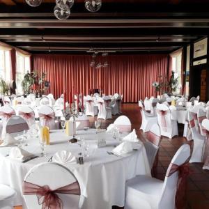 Un salón de banquetes con mesas y sillas blancas. en Burg Wassenberg, en Wassenberg