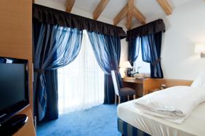 ein Schlafzimmer mit blauen Vorhängen, einem Bett und einem Schreibtisch in der Unterkunft Hotel Rotwand in Leifers + 60 Fotos