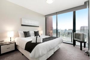 a bedroom with a large bed and a tv at Docklands Private Collection - NEWQUAY in Melbourne