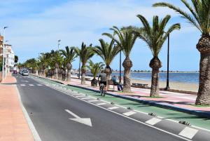 a person riding a bike down a street with palm trees at Mar Menor Lo Pagan Apartment in San Pedro del Pinatar