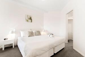 a white bedroom with a large white bed with white sheets at Docklands Private Collection - NEWQUAY in Melbourne