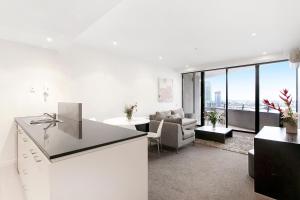 a white kitchen with a living room with a couch at Docklands Private Collection - NEWQUAY in Melbourne