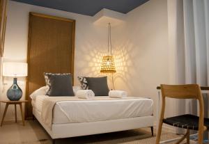 a bedroom with a bed with a lamp and a chair at YOU & CO. Saler Beach Boutique in Valencia