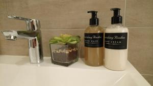 dos botellas de odorizantes sentadas en el lavabo del baño en Hamilton Garden Suites en Parklands