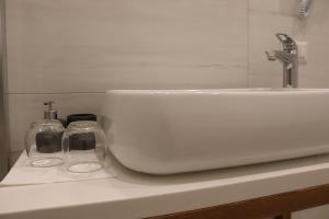 een witte wastafel en twee glazen op een aanrecht bij B&B JOELE in Tropea +33 foto's