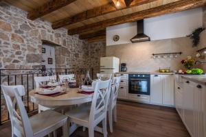 a kitchen with a table and chairs in a room at Stone Villa Katarina with pool in Klimno