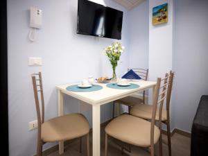 a small white table with chairs and a tv on a wall at Al Chiaro di Luna in Fondi