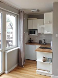 a kitchen with white cabinets and a large window at A może morze? in Sztutowo