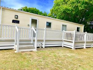 a mobile home with a porch and white railing at Forest beach Shorefield Park in Lymington