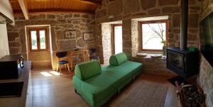 a living room with a green couch and a tv at Casa da Mina in Carapito