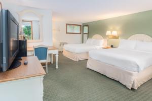 a hotel room with two beds and a flat screen tv at Ocean Park Inn Cape Cod in Eastham