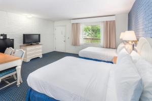 a hotel room with two beds and a desk and a television at Ocean Park Inn Cape Cod in Eastham +31 photos