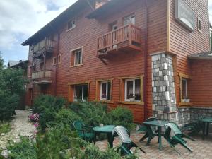 a building with tables and chairs in front of it at Pensiunea Fara Nume in Buşteni