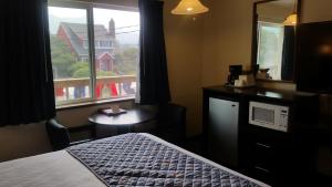 a bedroom with a bed and a window with a view at Tradewinds Motel in Rockaway Beach