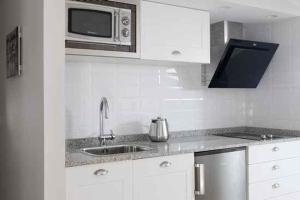 a white kitchen with a sink and a microwave at Apartamentos Turísticos Beethoven Haro in Haro