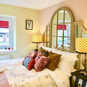una camera da letto con un letto con cuscini e due finestre di The Little Beech Tree a Linlithgow