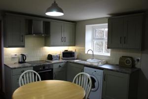 cocina con armarios verdes y mesa de madera en Hillcrest Cottage en Carrickfergus