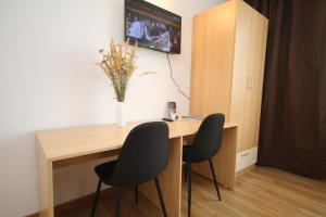 a desk with two chairs and a vase of flowers at Apartment Brownie in Timişoara