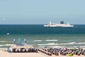 a cruise ship in the ocean with chairs and a beach at Strand-Hotel Hübner in Warnemünde