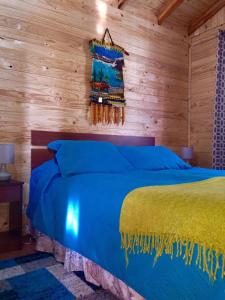 a bedroom with a blue bed in a wooden room at Cabañas Alfa Colbun Machicura in Linares