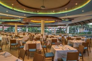 un ristorante con tavoli e sedie bianchi in una stanza di Viva Dominicus Palace by Wyndham, A Trademark All Inclusive a Bayahibe