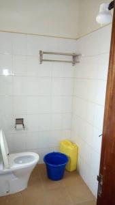 a bathroom with a toilet and a blue bucket at Kanberra Hotel in Lira