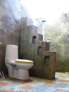 a bathroom with a toilet with a painting on the wall at Rachavadee Bankrut Resort in Ban Krut