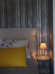 a bed with a yellow pillow next to a table with a lamp at Une Heure Bleue in Manosque