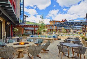 a patio with tables and chairs and a fire pit at Limelight Hotel Snowmass in Snowmass Village