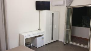 een kamer met een wit bureau en een tv aan de muur bij Marina bay house in Rossano
