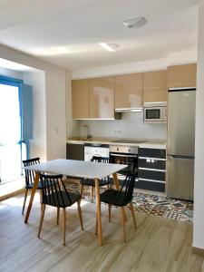 eine Küche mit Tisch und Stühlen und einem Kühlschrank in der Unterkunft Apartamentos Turísticos Casa Dina in Rinlo