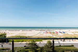 a beach with a bunch of people and flags at Strand-Hotel Hübner in Warnemünde