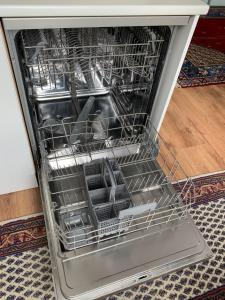 an open dishwasher with dishes inside of it at Ottenson Saaremaa apartment in Salme