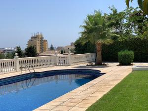 einen Pool mit einem weißen Zaun und einer Palme in der Unterkunft Apartamentai in Torremolinos