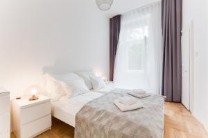 um quarto branco com uma cama e uma janela em The Dancing House Residence em Praga