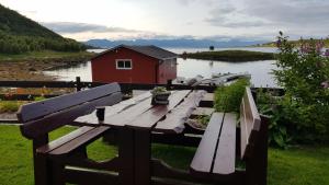 stół piknikowy i czerwony dom nad jeziorem w obiekcie Prima Lofoten w mieście Myrland