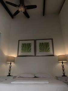 a bedroom with a ceiling fan and a bed with two lamps at Palmira Hostel in Tegucigalpa