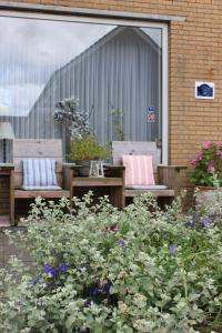 eine Terrasse mit zwei Bänken und ein paar Blumen in der Unterkunft Kerstins Bed and Breakfast in Egmond aan Zee