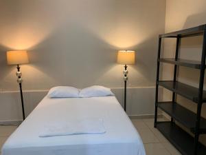 a bedroom with a white bed with two lamps at Palmira Hostel in Tegucigalpa