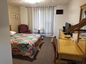 Habitación de hotel con cama y escritorio con TV. en Knights Inn Woodstock, en Woodstock