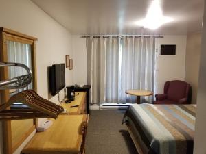 Habitación de hotel con cama, escritorio y TV. en Knights Inn Woodstock en Woodstock