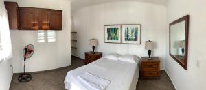 a bedroom with a white bed and a mirror at Palmira Hostel in Tegucigalpa