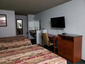 Cette chambre comprend deux lits et un bureau avec une télévision. dans l'établissement Budget Inn, à Fallon