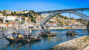 um grupo de barcos na água debaixo de uma ponte em Porto City Hotel em Porto