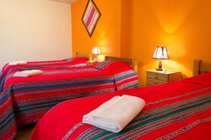 two beds in a room with orange walls at Sonqo Killa del Colca in Chivay