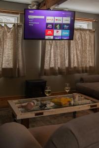 a tv hanging above a table in a living room at The Broken Dish - Full Cottage Apartment in Mendham