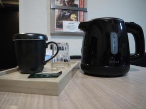 a black coffee maker and a cup on a table at Hotel Route-Inn Osaka Kishiwada -Higashikishiwada Ekimae Kansai Airport- in Kishiwada